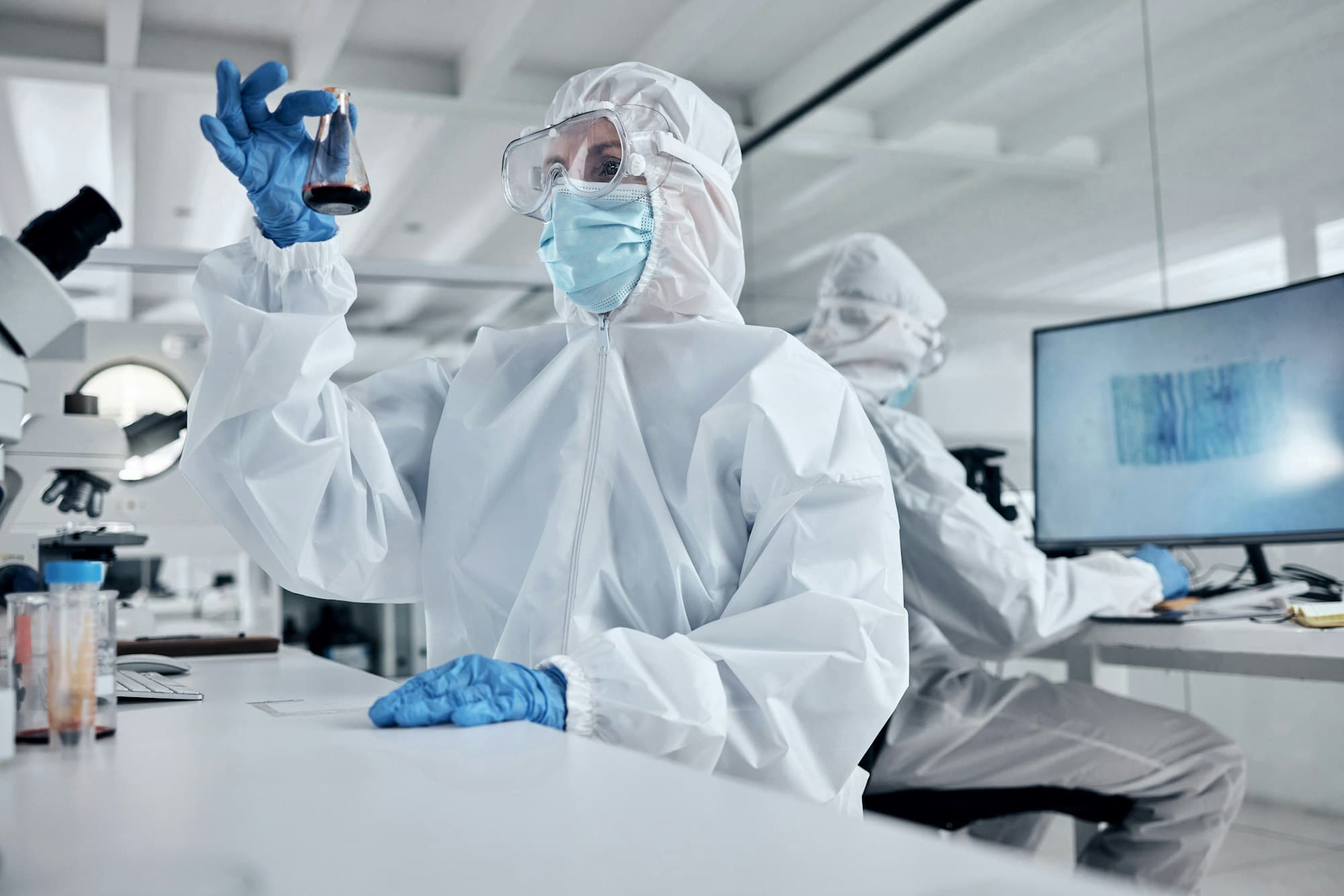 Medical professional in a laboratory examining DNA test samples and genetic screening results on a computer screen