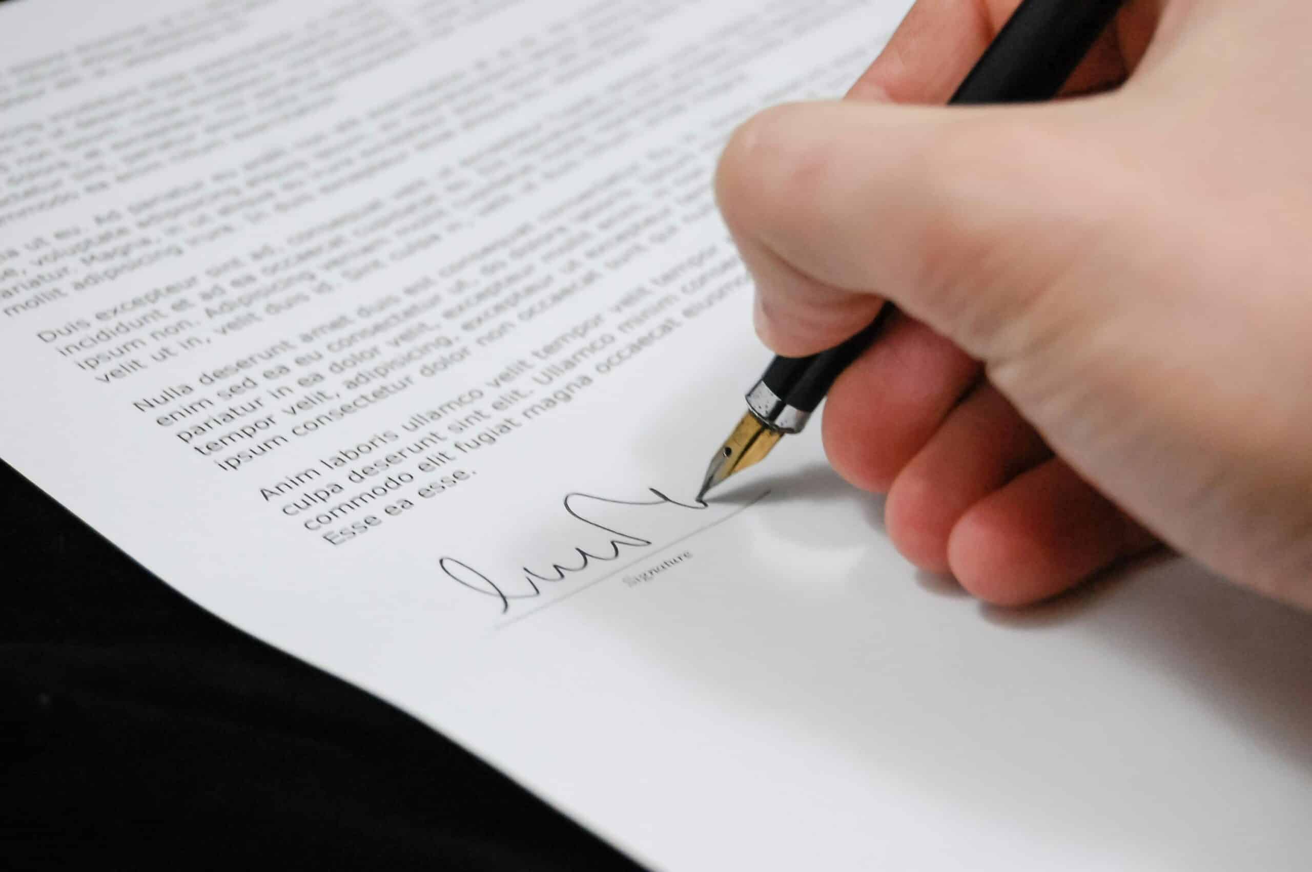 Close-up of an employment contract document with a pen resting on a non-compete clause section, placed on a modern office desk