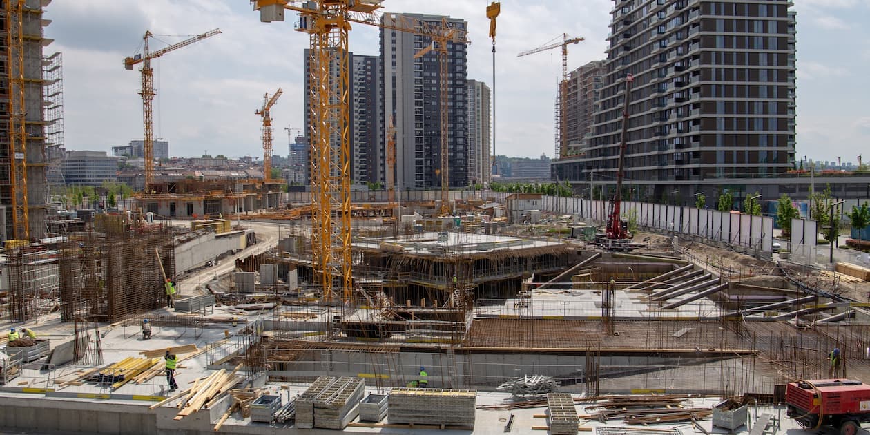 Aerial view of a modern commercial development under construction on leased land in Dubai, showing cranes, building frameworks, and