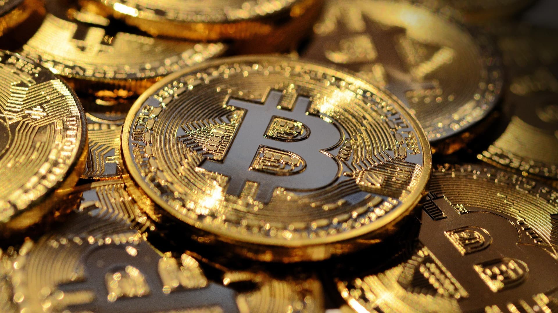 Close-up of a laptop screen displaying cryptocurrency exchange trading interface with Dubai skyline visible through office window in