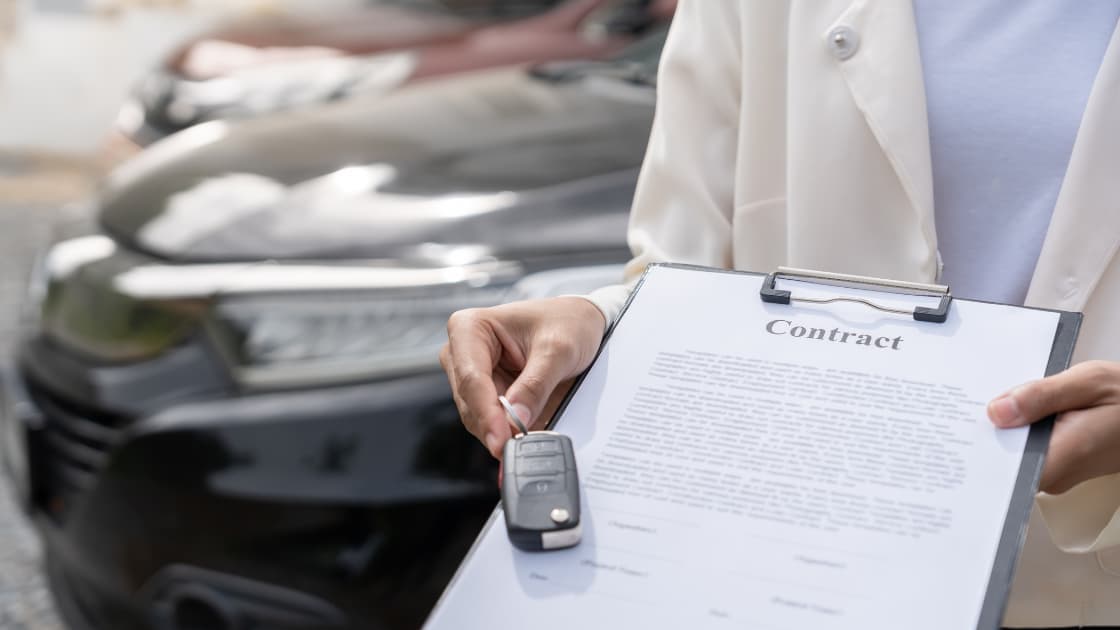 Close-up of a car loan financing contract document with a Saudi Arabian vehicle registration certificate and promissory note on a desk