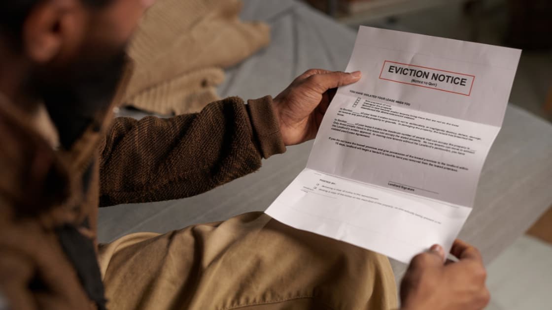 Close-up of multiple post-dated rent cheques with a red 'dishonoured' stamp from a UAE bank, placed on a tenancy contract document