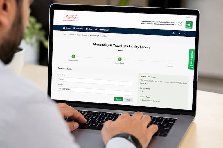 UAE passport and Emirates ID beside a laptop showing an official travel ban check portal